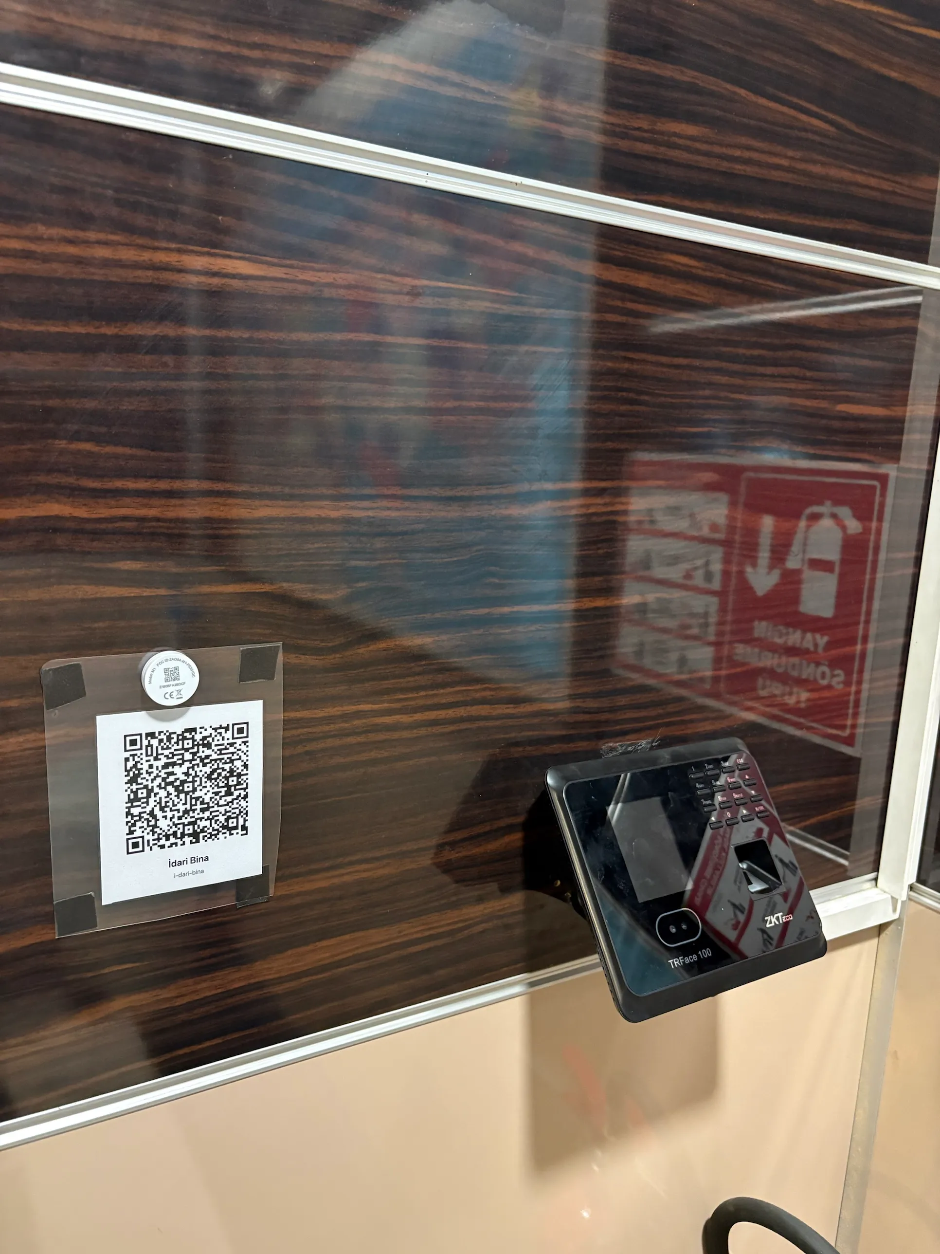 İdari Bina girişindeki QR kod etiketi, hemen yanında bantla kapatılmış yüz tanıma cihazı